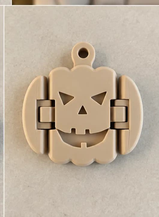 Flexi pompoen-sleutelhanger van voren: beige pompoen met gezichtje, twee scharnierende zijkanten en een oogje bovenaan