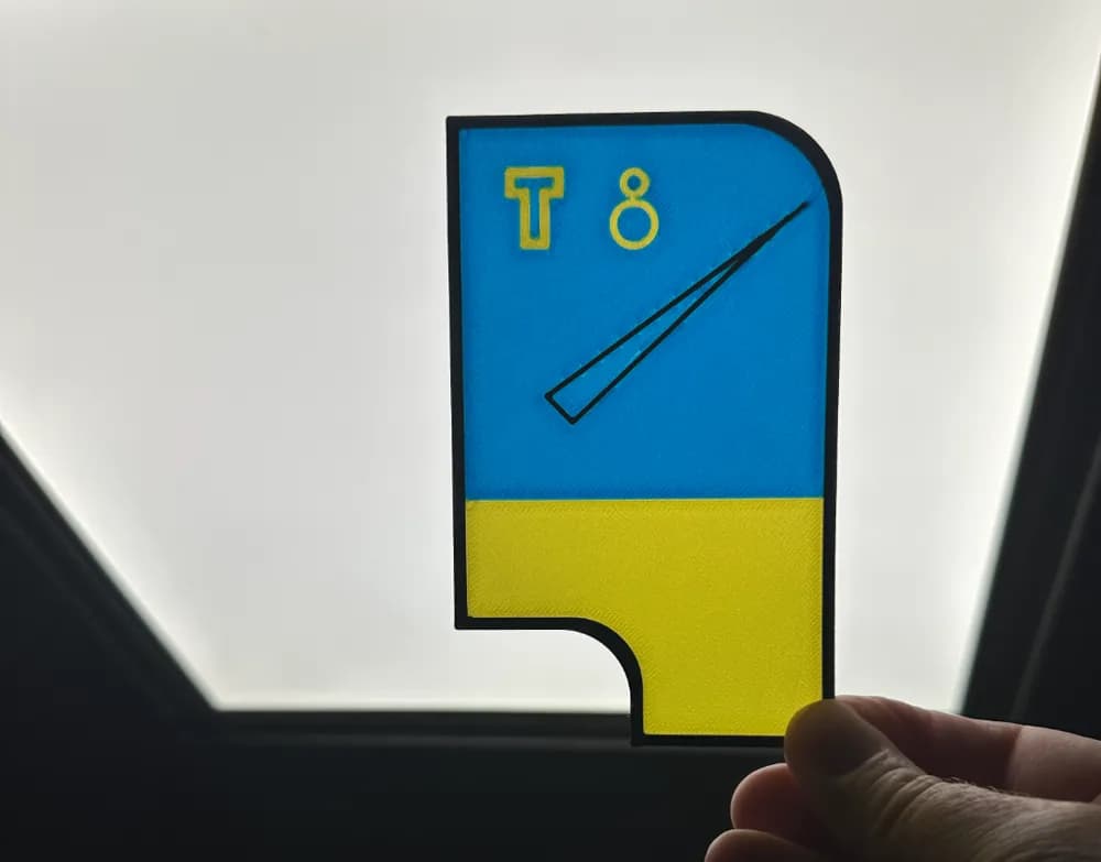 Verlichte blauw-gele testvoorzijde voor een 3D-geprinte lichtbak, voor een lichtbron gehouden.