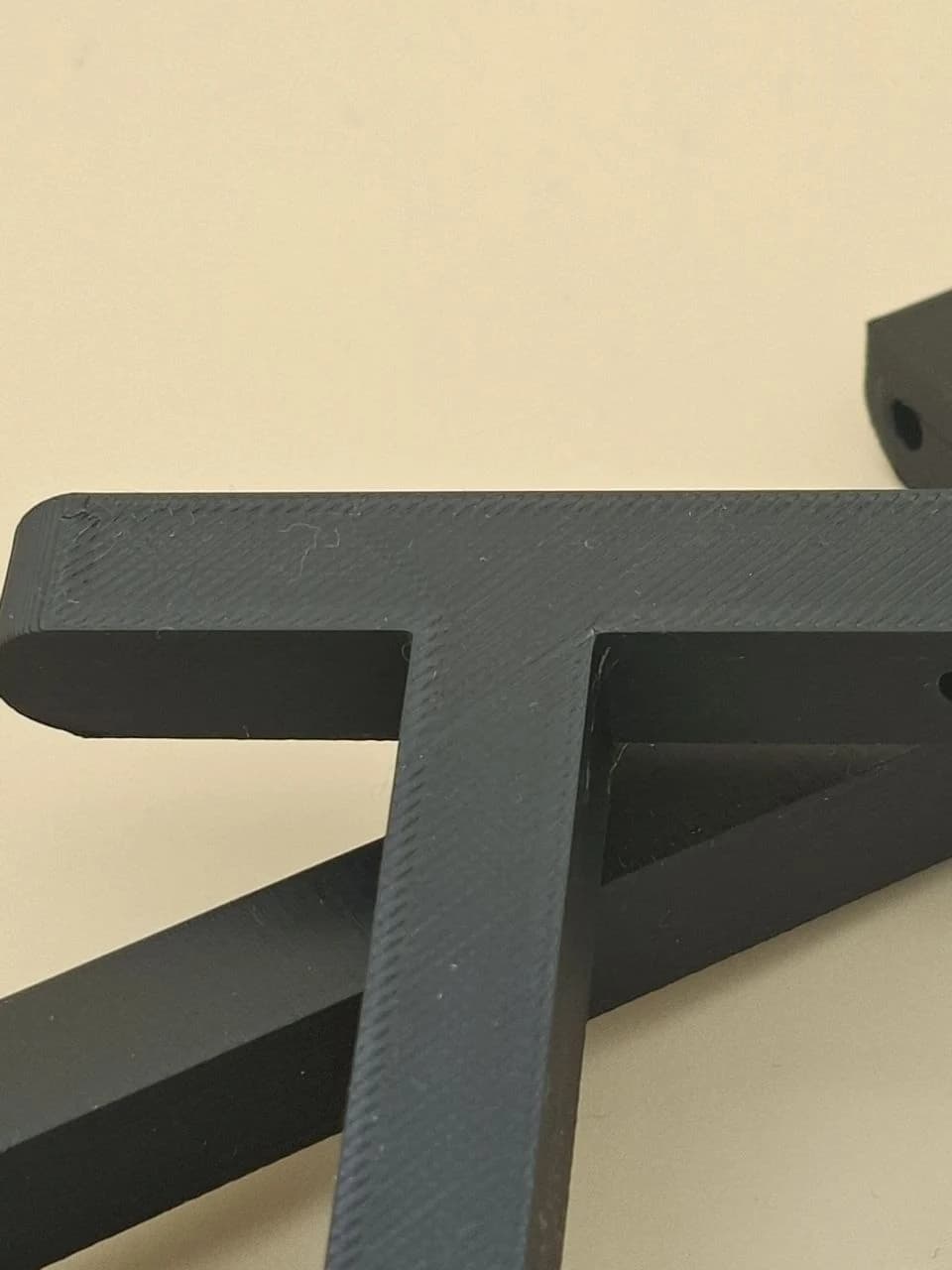 Top view of the black version 2 bracket showing the FDM extrusion pattern.