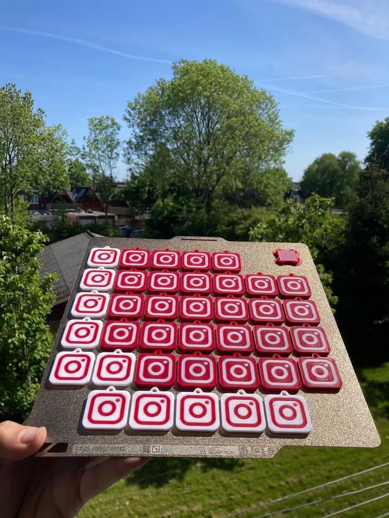 A full build plate of dozens of red and white keychains, held up against a blue sky.