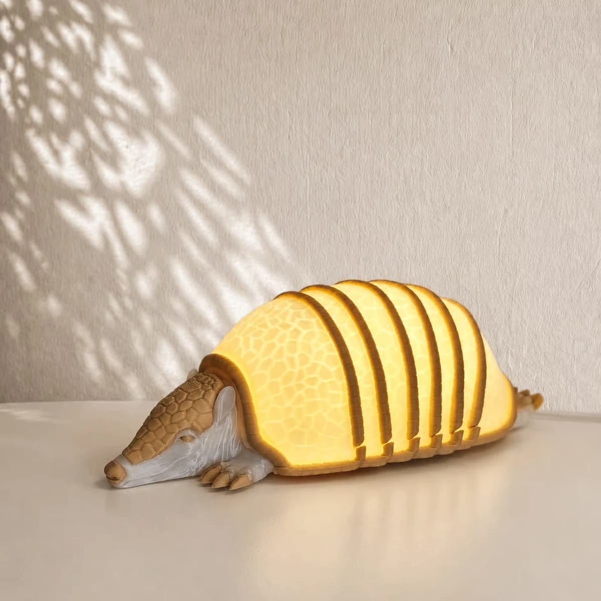 Makerbeeld van de Armadillo sfeerlamp: laag gordeldier met lange snuit en geel verlicht pantser tussen bruine ribben; voorbeeld van de ontwerper