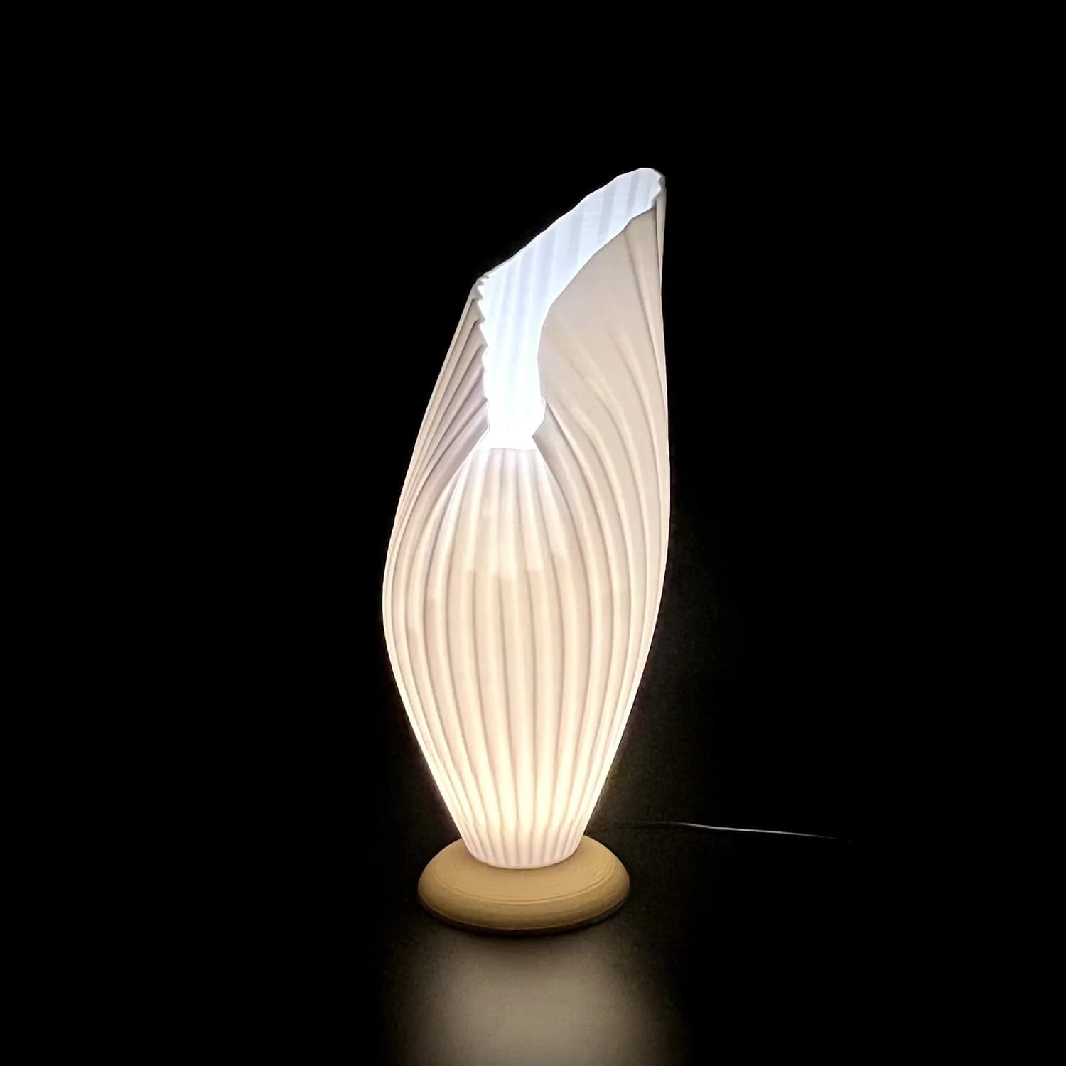 Lit FoldedInside creator example with ribbed asymmetric open shade and round base against a dark background