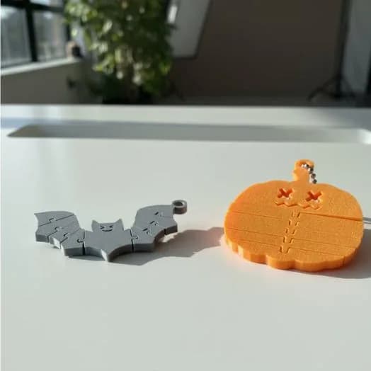 Spookyflex-trio – grijze vleermuis en oranje pompoen met kettinkje op een witte tafel