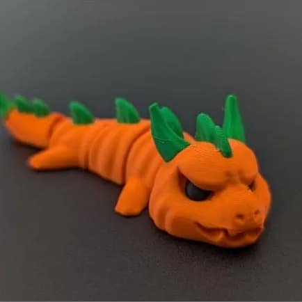 Pompoendraak – oranje draak met pompoenkop en groene stekels, languit op een donkere ondergrond